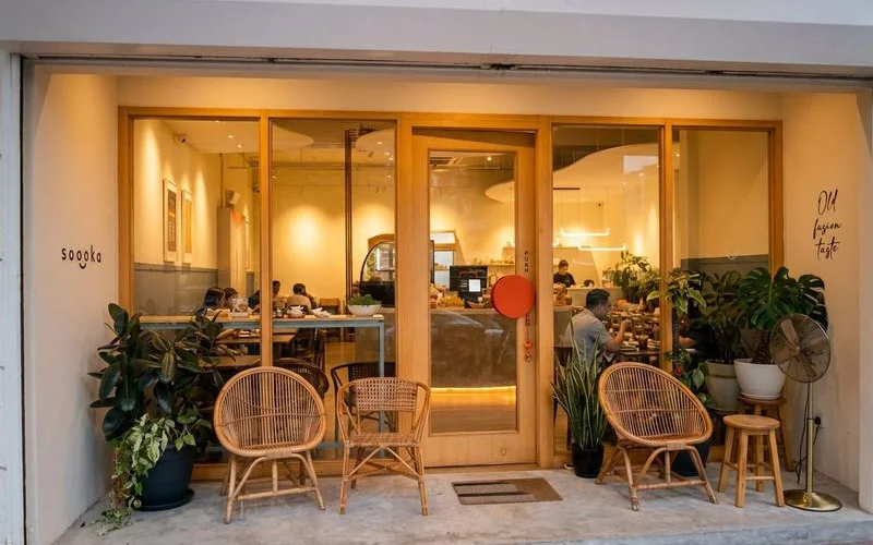 The warm glowing exterior of Soooka Cafe in the evening with welcoming light spilling through the windows onto the street